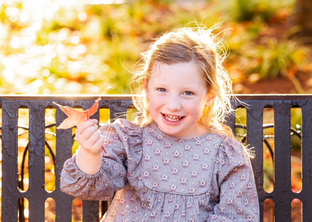 Girl holding up a leaf with a big smile