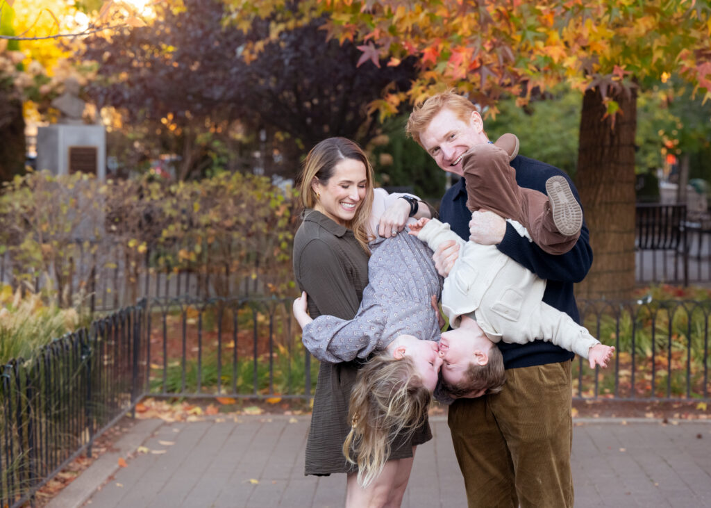 Kids upside down in a park in NJ surrounded by fall trees. 
