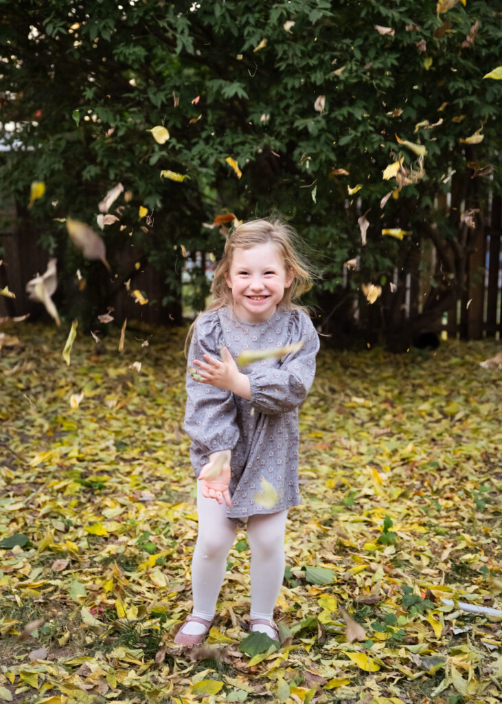 Girl throwing loeaves into the hair with a. happy face. 