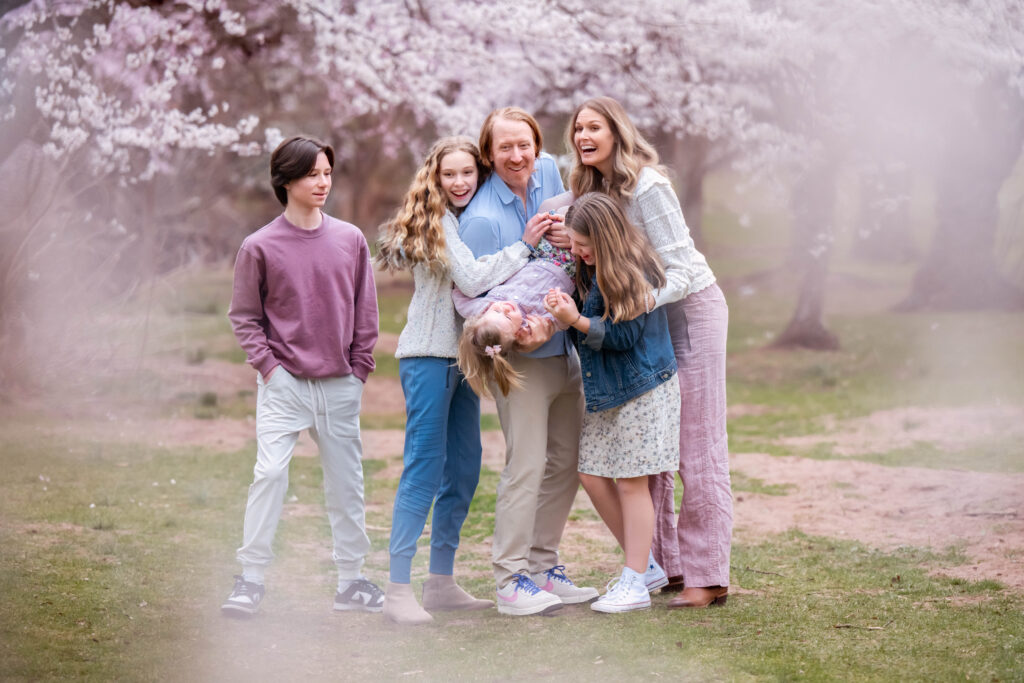 family of four laughing together in spring flower field