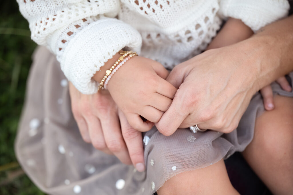 Close-up of a mother and child holding hands during a family photography session.