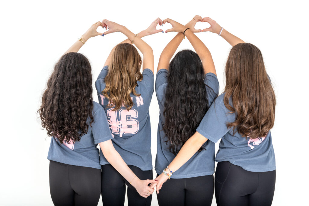 Friends forming heart shapes with their hands during a Sweet 16 photoshoot.