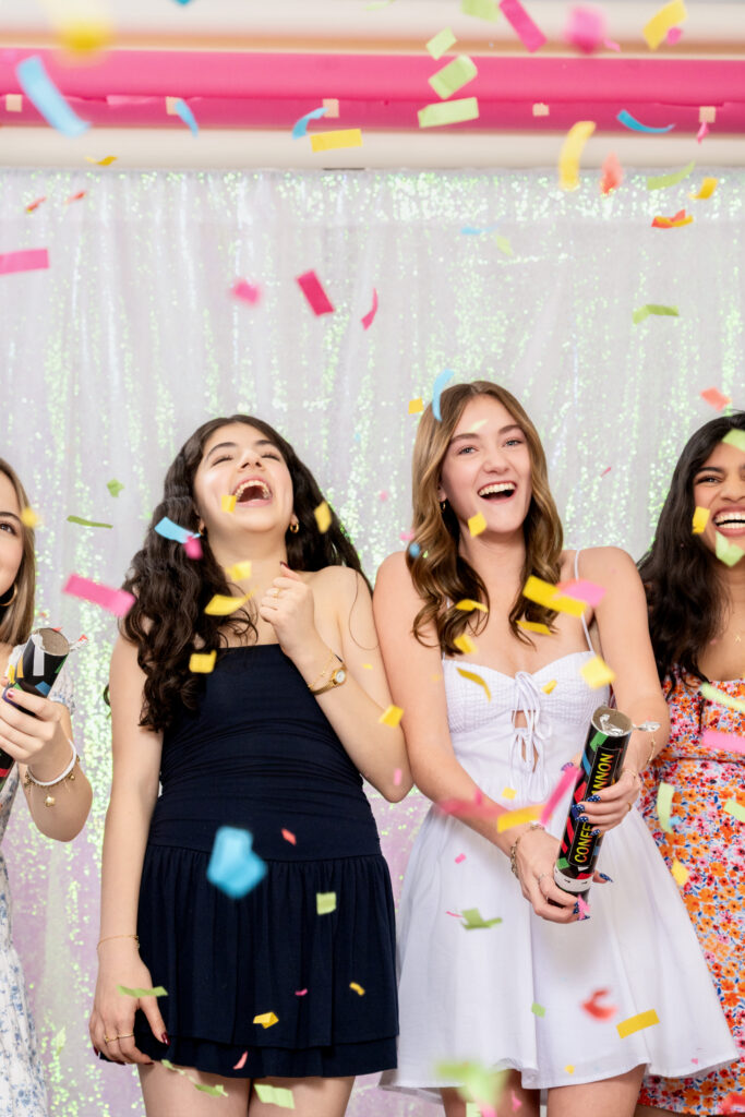 Taryn and her friends laughing together as colorful confetti falls around them.
